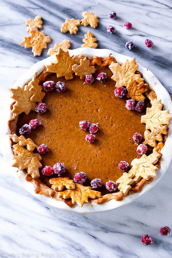 pumpkin pie garnished with sugared cranberries and pie crust designs