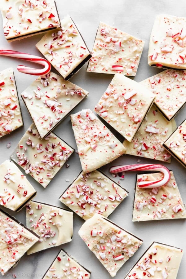 candy cane peppermint bark pieces with mini candy canes arranged on white parchment paper.
