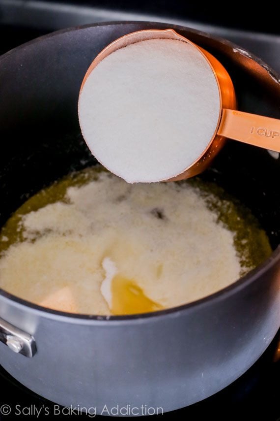 pouring sugar into melted butter in a saucepan on the stove