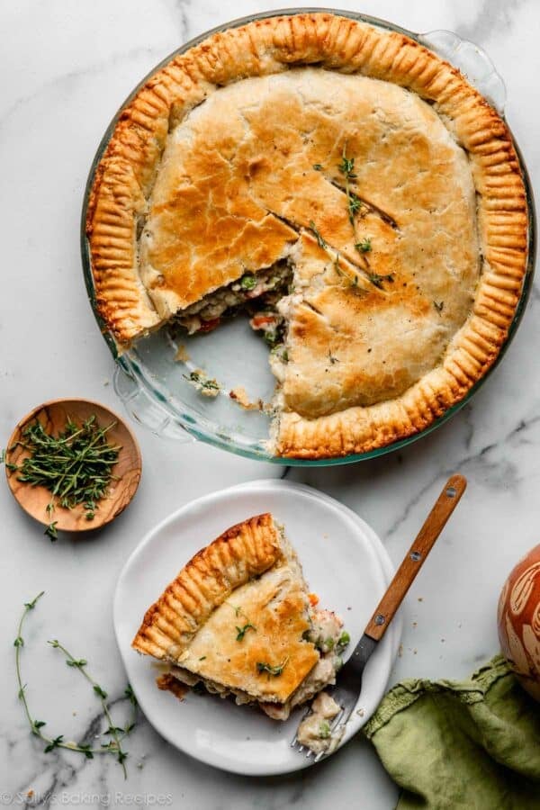 overhead photo of chicken pot pie with slice cut out and on white plate with fresh thyme.
