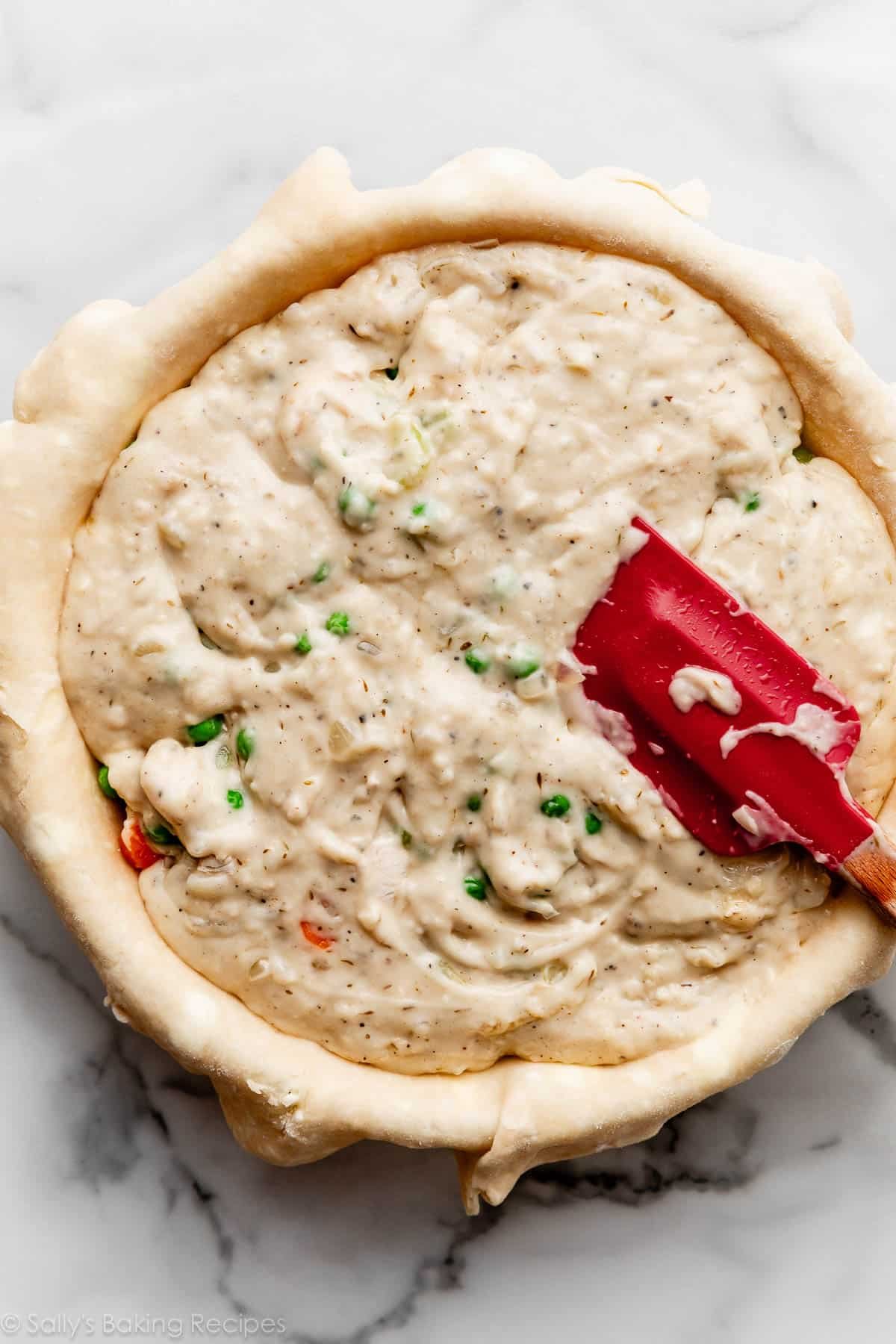 white gravy with peas and vegetables underneath in pie dough.