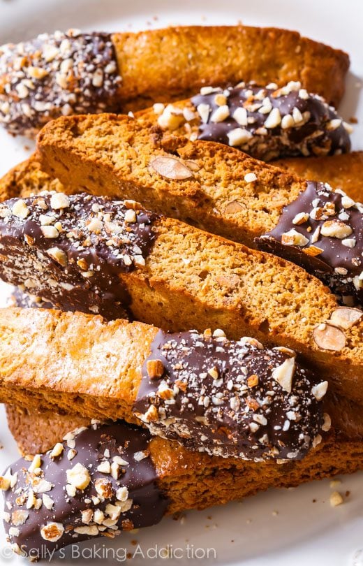 almond biscotti with part of each cookie dipped in chocolate on a white plate