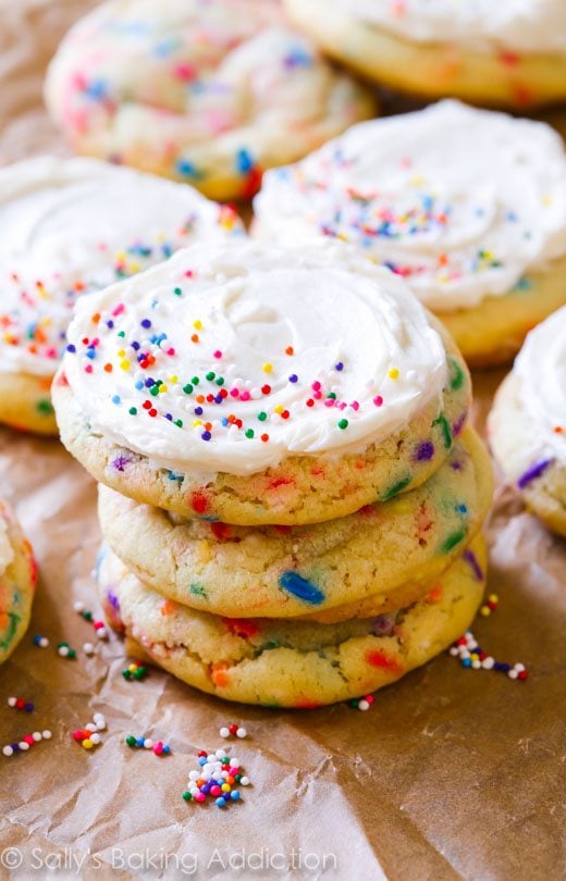 stack of sugar cookies with sprinkles topped with vanilla frosting and sprinkles