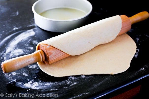 pizza dough rolled out with a wood rolling pin