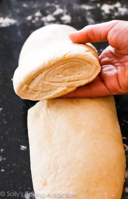 hand holding deep dish pizza dough showing the layers