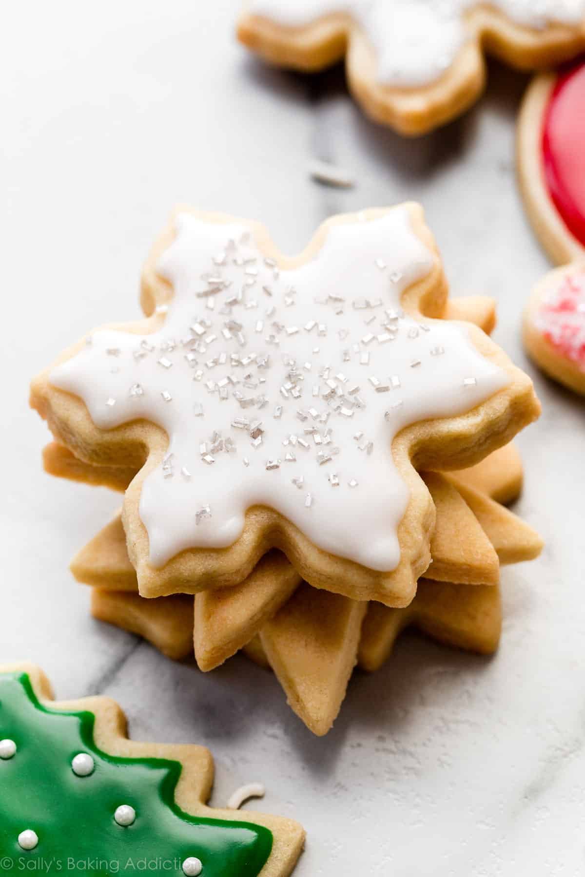 stack of snowflake sugar cookies with icing and silver sprinkles.