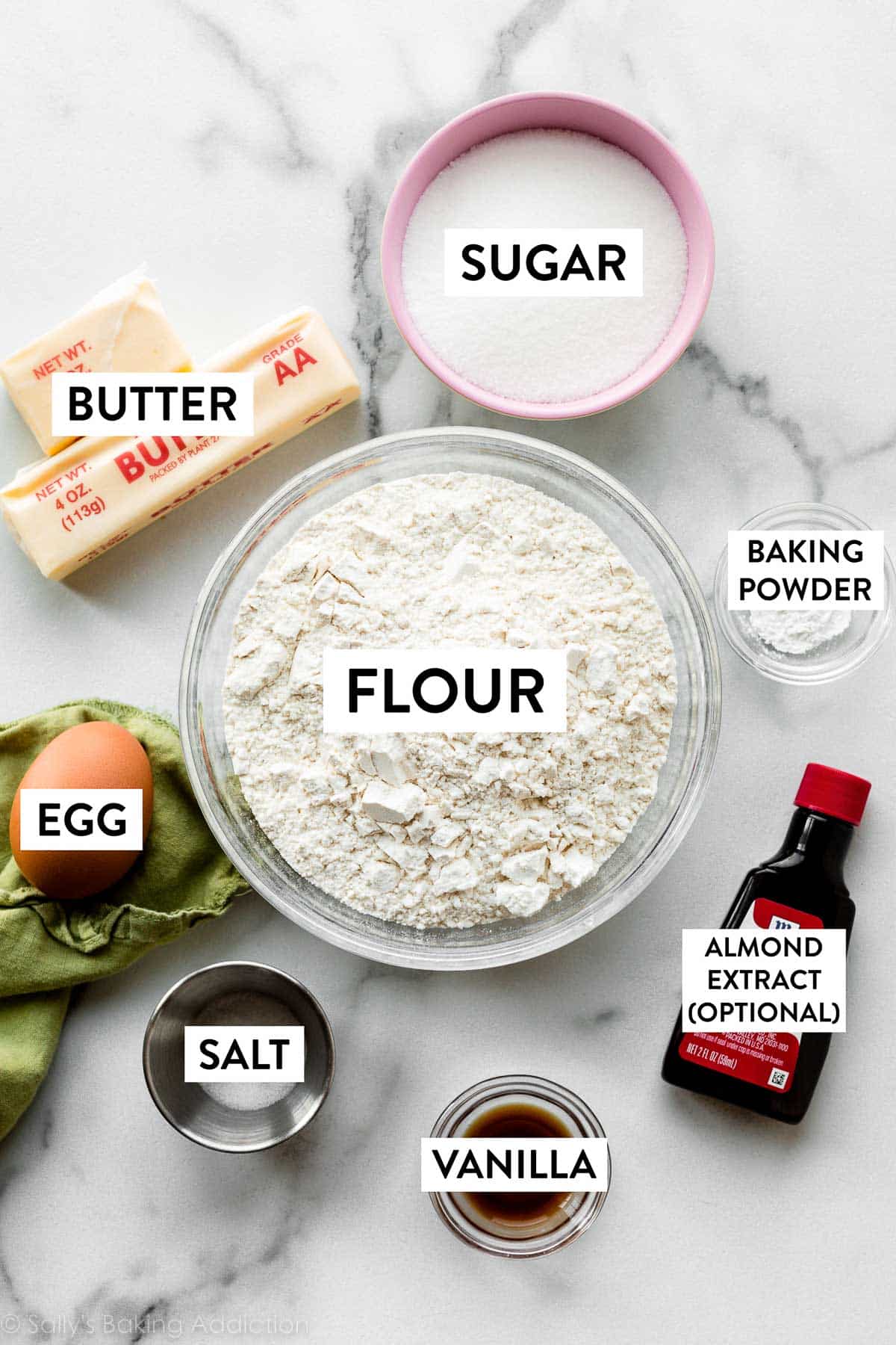 flour, sugar, butter, baking powder, egg, salt, and vanilla on marble counter.
