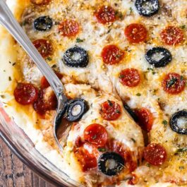 overhead image of pepperoni pizza dip in a glass baking dish with a spoon