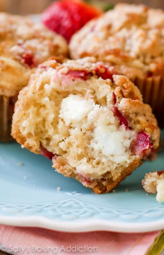 strawberry cheesecake muffins with one cut in half showing the inside on a blue plate