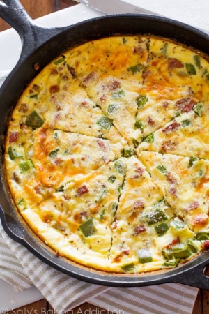 overhead image of cheesy sausage quiche in a skillet and cut into slices