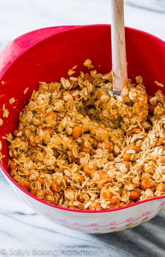 honey roasted peanut butter granola in a red bowl with a spatula