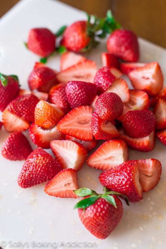 sliced strawberries on a white cutting board