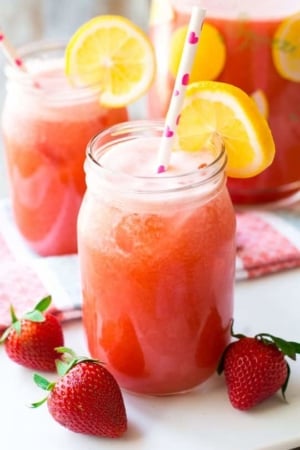glasses of honey sweetened strawberry lemonade with straws and lemon slices