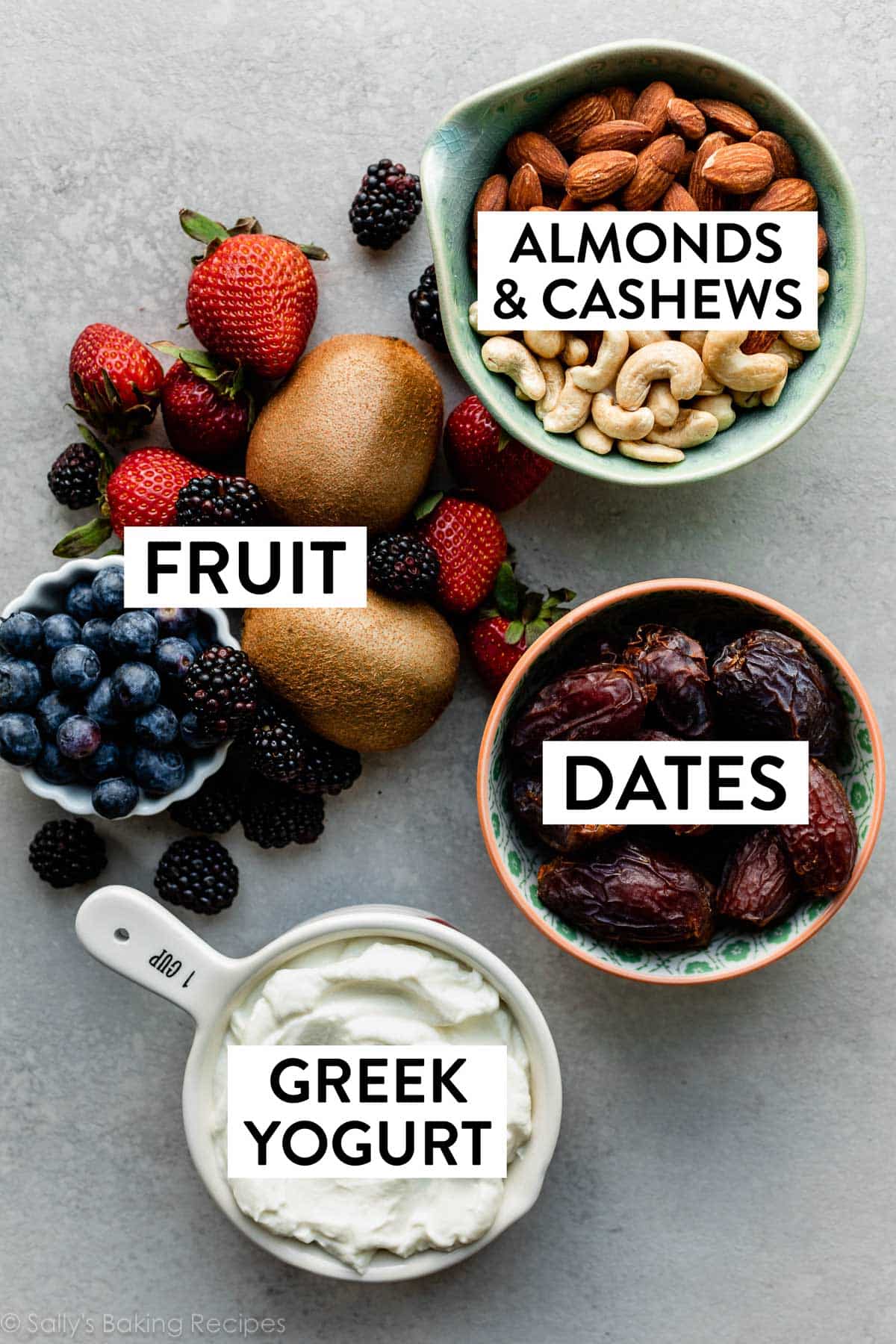 ingredients in bowls including almonds and cashews, dates, Greek yogurt, and fresh fruit.