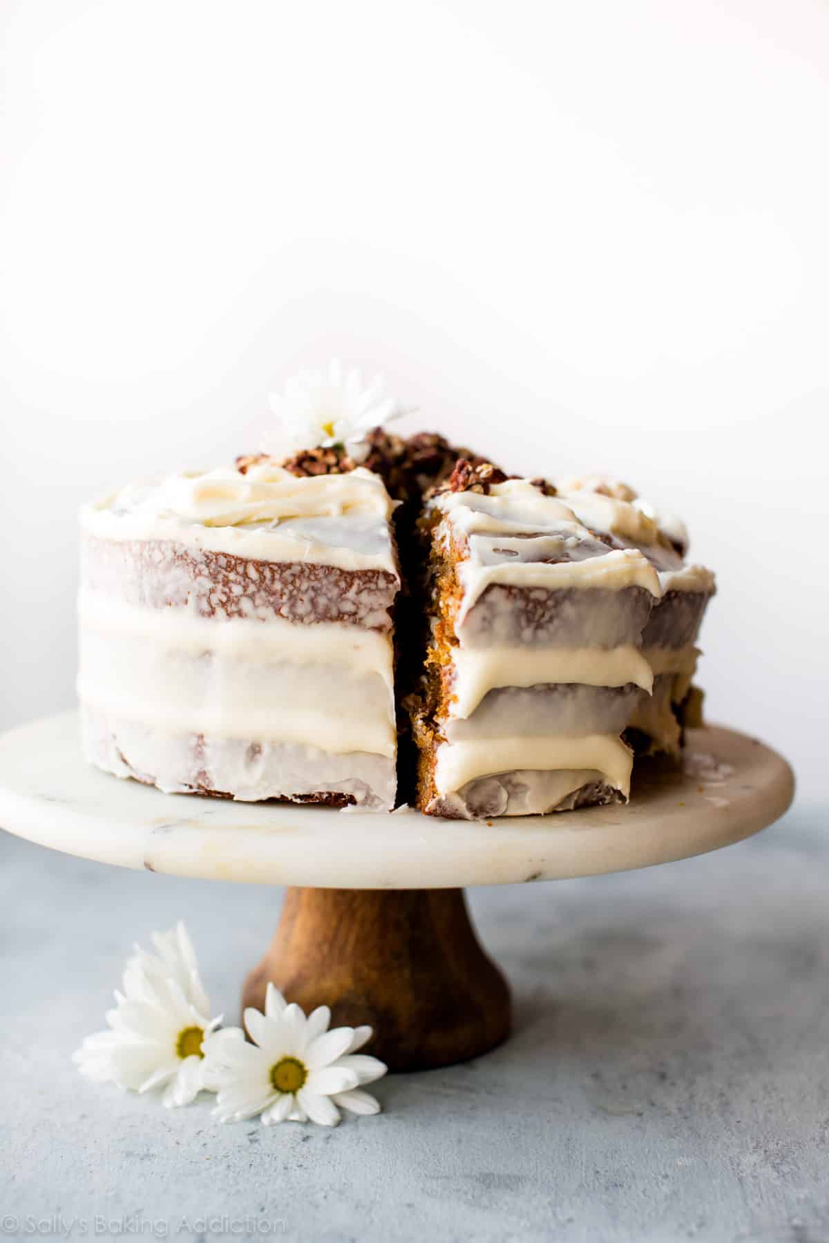 Carrot cake with cream cheese frosting on marble and wood cake stand