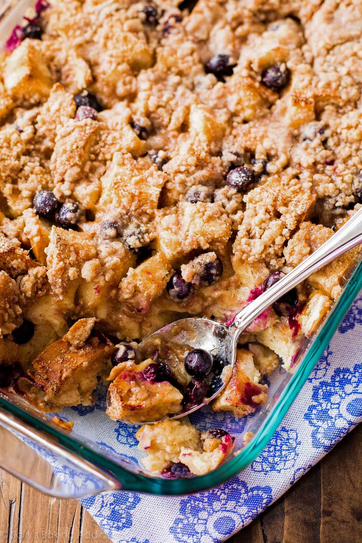 blueberry french toast casserole in a glass baking dish with a serving spoon