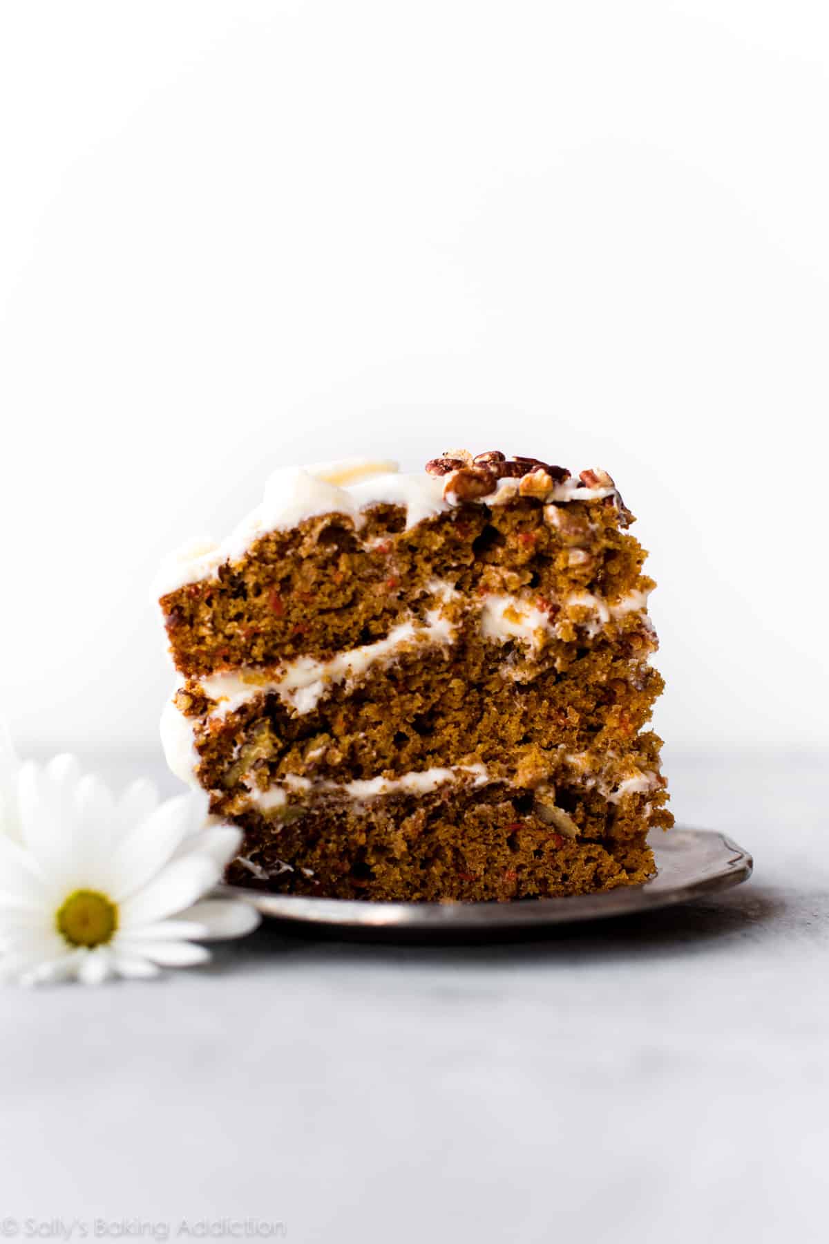 slice of carrot cake with cream cheese frosting on silver plate