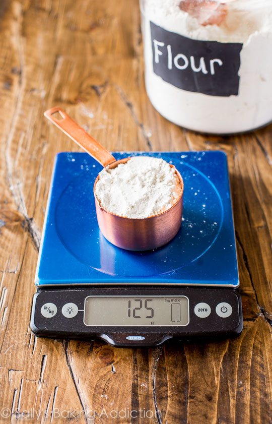 a measuring cup with flour on a kitchen scale