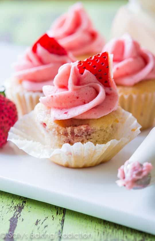 strawberry cupcakes topped with strawberry frosting on a white serving tray