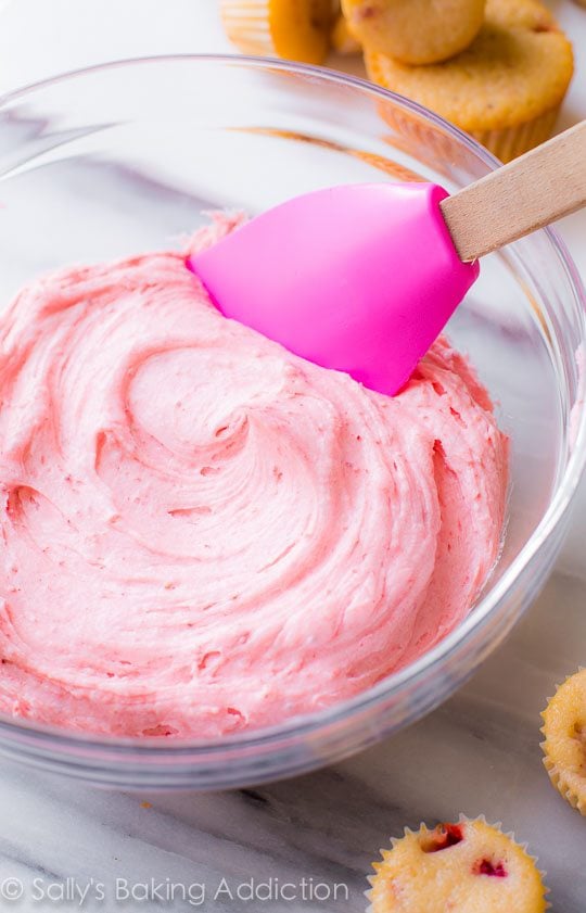 strawberry buttercream frosting in a glass bowl with a spatula