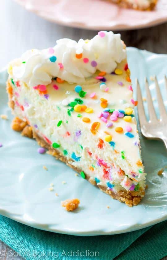 slice of funfetti cheesecake on a blue plate with a fork