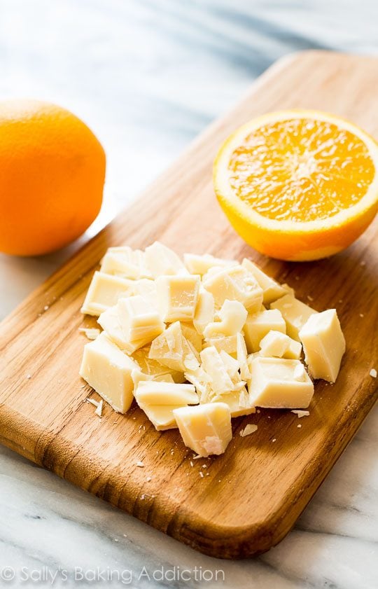 chopped white chocolate and half and orange on a wood board