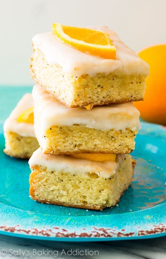 stack of glazed orange poppy seed bars on a blue plate