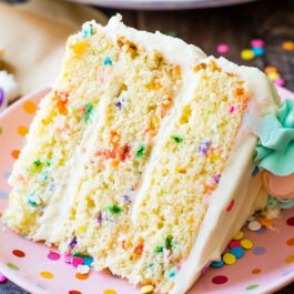 slice of funfetti layer cake on a pink polka dot plate