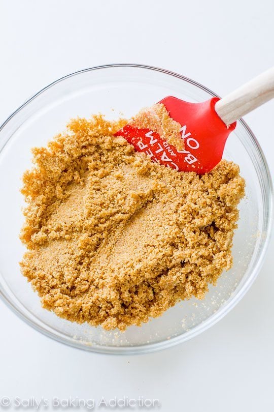 graham cracker crust mixture in a glass bowl with a spatula