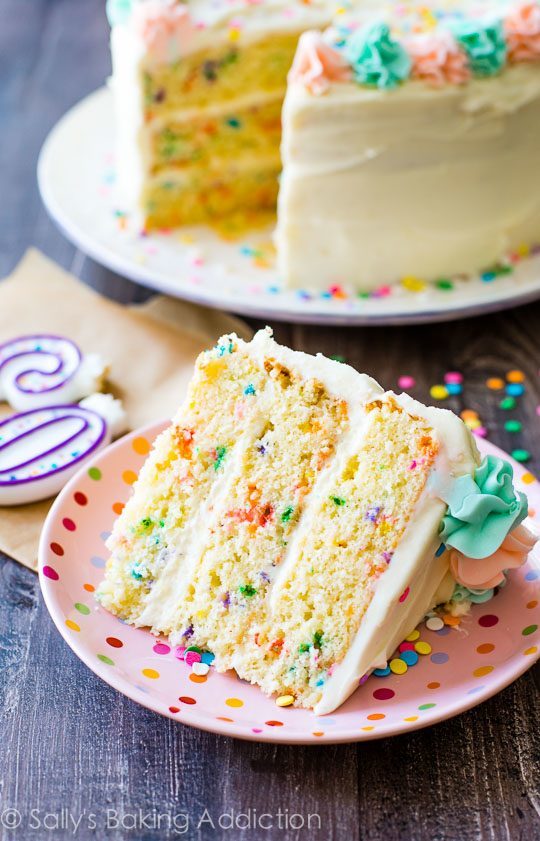 slice of funfetti layer cake on a pink polka dot plate