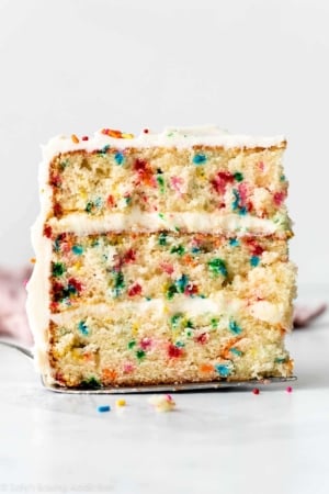 slice of Funfetti confetti birthday cake with vanilla buttercream sitting on cake server.