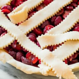 pie crust strips on top of cherry pie with text overlay that says baking basics a series