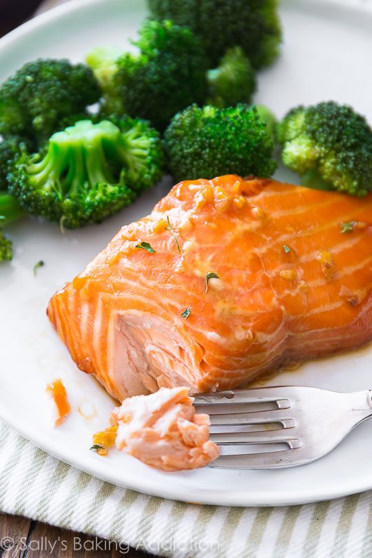 garlic honey ginger glazed salmon on a white plate with a fork and broccoli