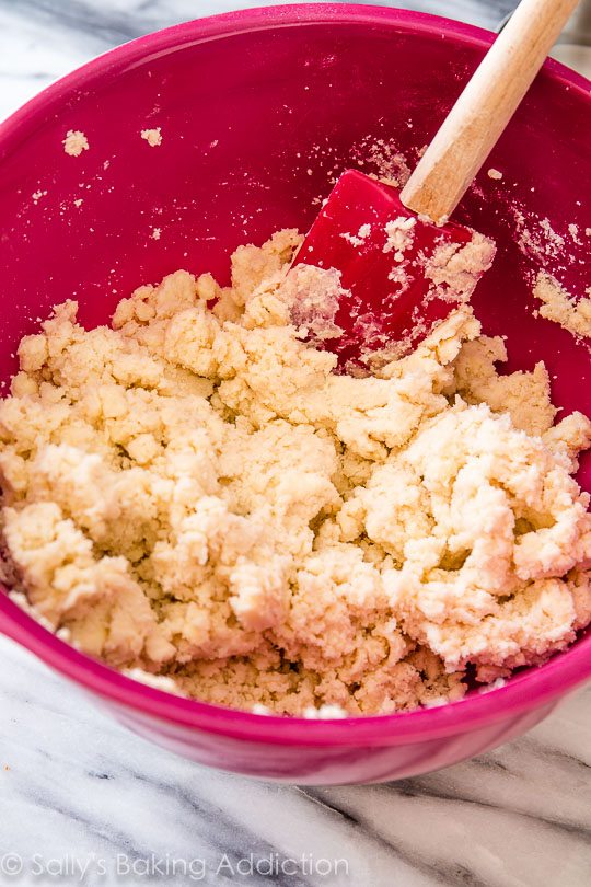 shaggy pie dough mixture in a pink bowl with a spatula