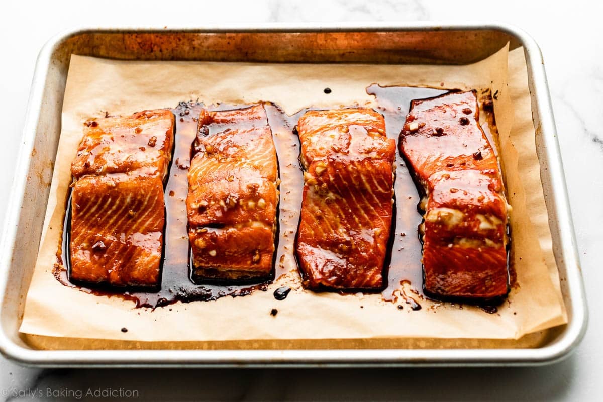 4 filetes de salmón al horno en una bandeja para hornear pequeña forrada con papel pergamino.