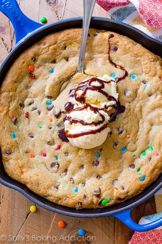 M&Ms chocolate chip skillet cookie topped with ice cream in a blue skillet