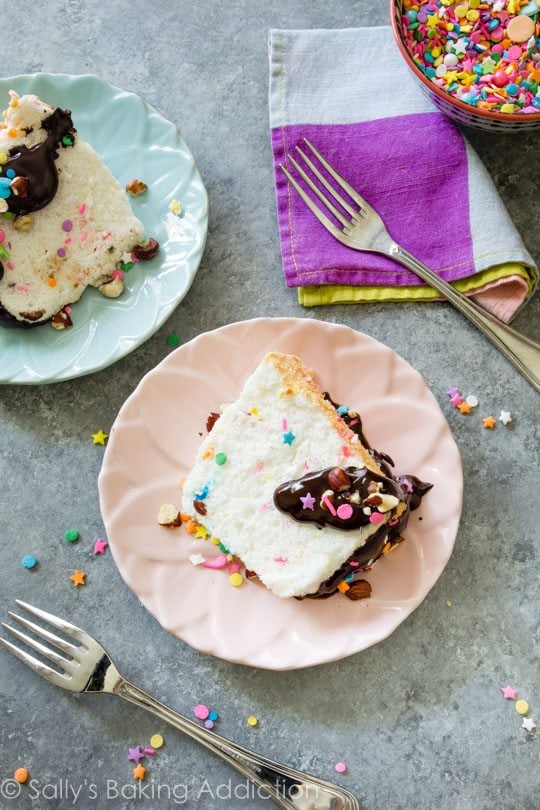 slices of sprinkle angel food cake on pink and blue plates with forks