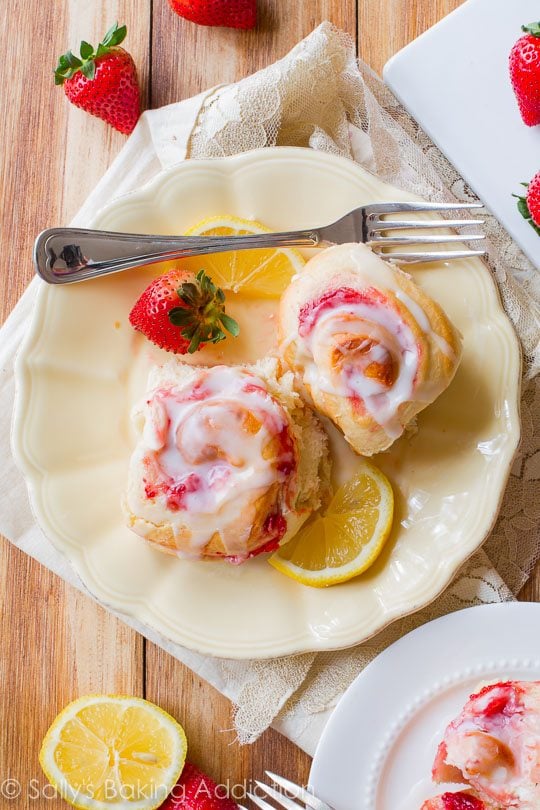overhead image of strawberry sweet rolls with lemon glaze on a cream plate with a fork