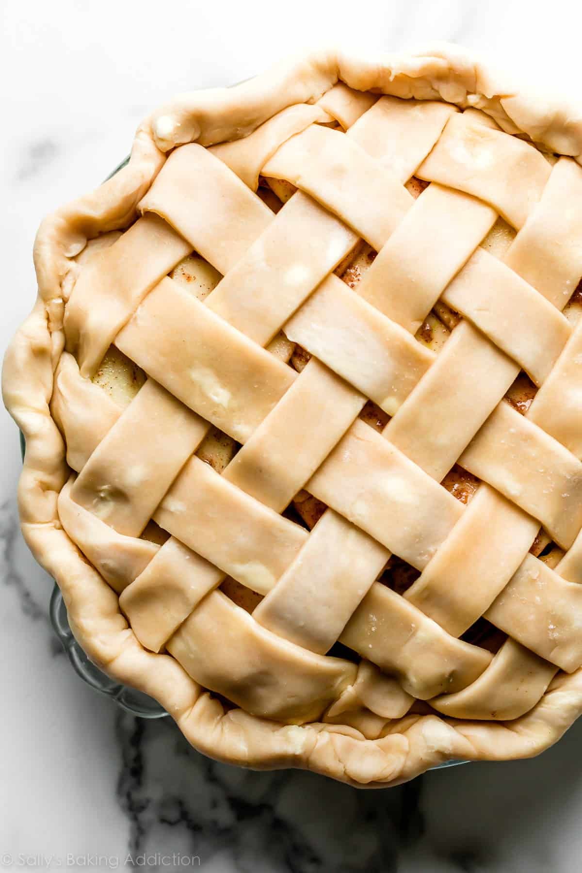pie crust in lattice design on top of apple pie sitting in glass pie dish.