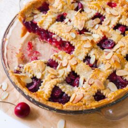 cherry pie in a glass pie dish with toasted almonds on top