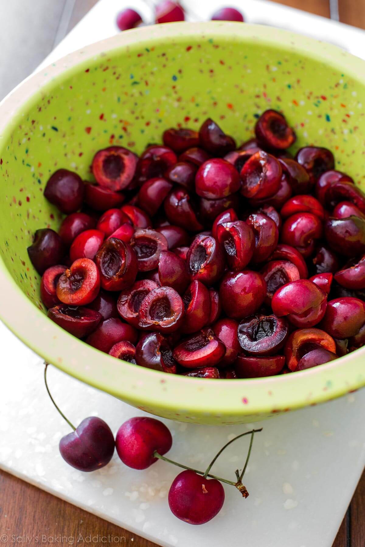 pitted and halved cherries in a green bowl