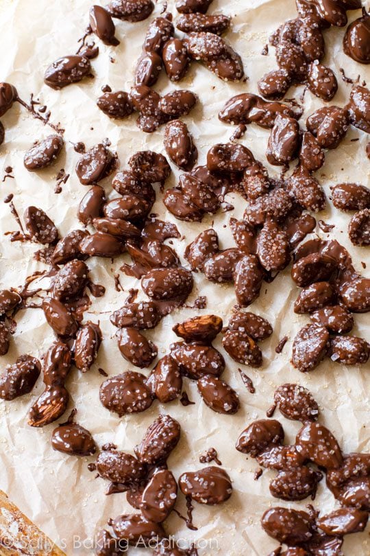 chocolate dipped almonds on parchment paper with sea salt on top