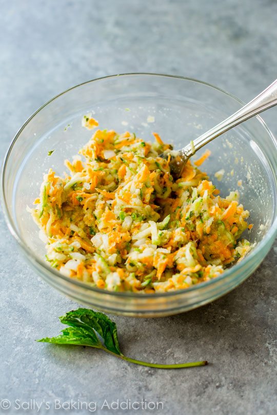 shredded zucchini and sweet potatoes in a glass bowl with a spoon