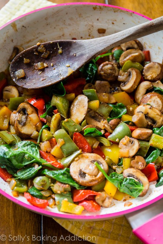 sautéed vegetables in a skillet with a wood spoon