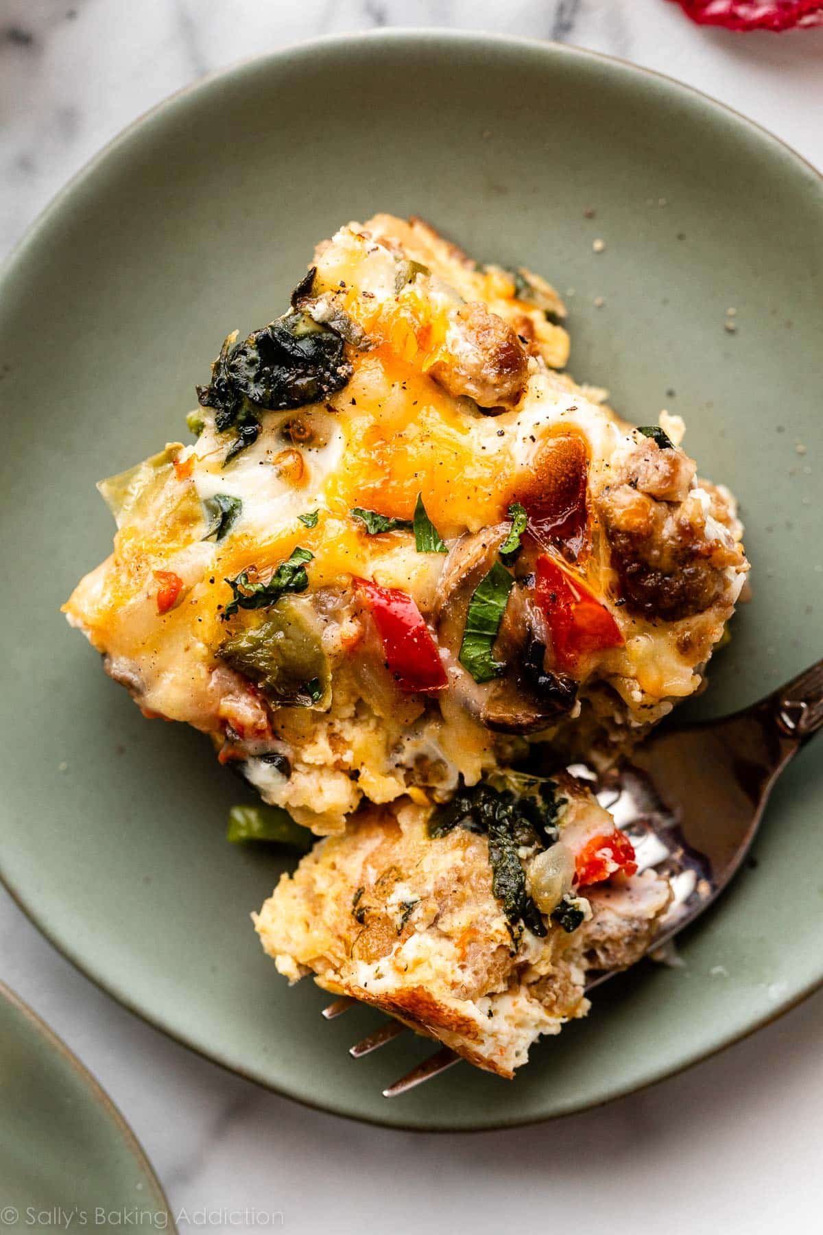 overhead photo of slice of egg breakfast casserole with spinach, sausage, cheese, and peppers.