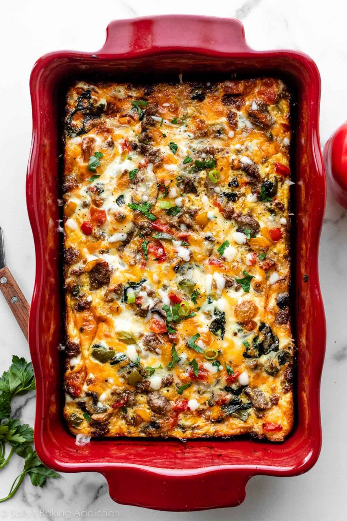 baked egg cheese and sausage breakfast casserole in red casserole dish.