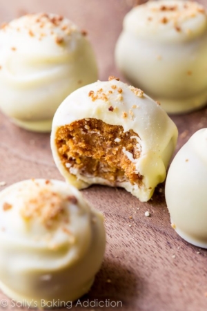 pumpkin spice truffles coated in white chocolate with a bite taken out of one showing the inside