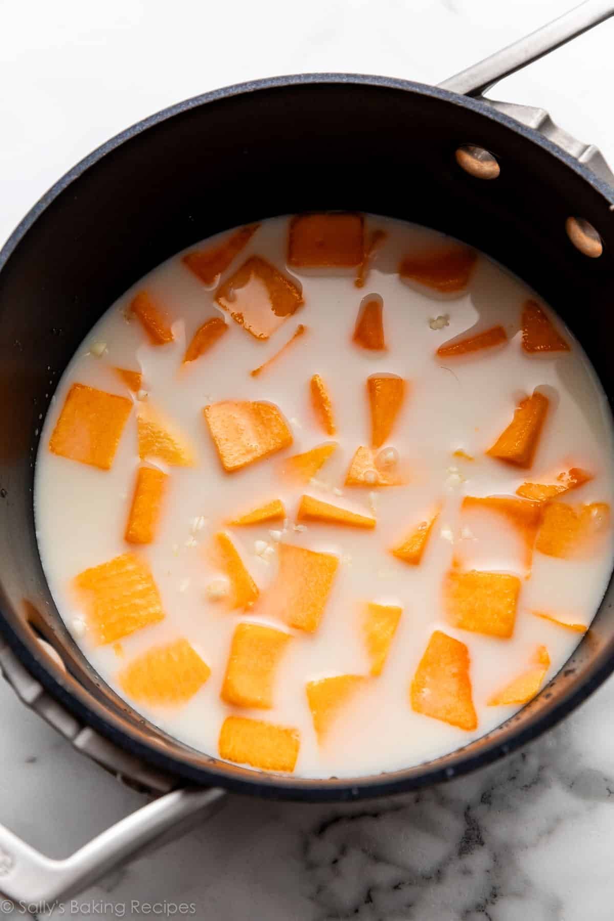 cubed squash floating in milk in saucepan.