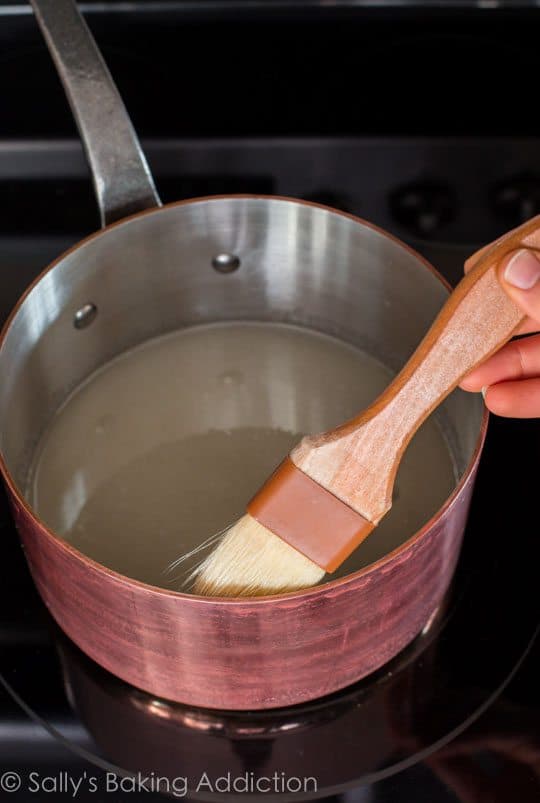 hand holding a pastry brush in a saucepan