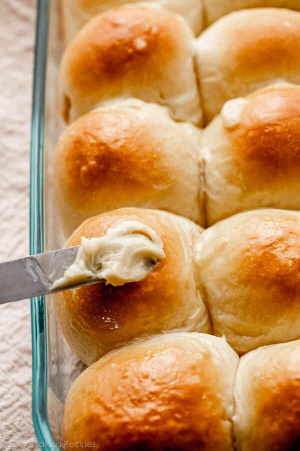 spreading honey butter on baked bread rolls.